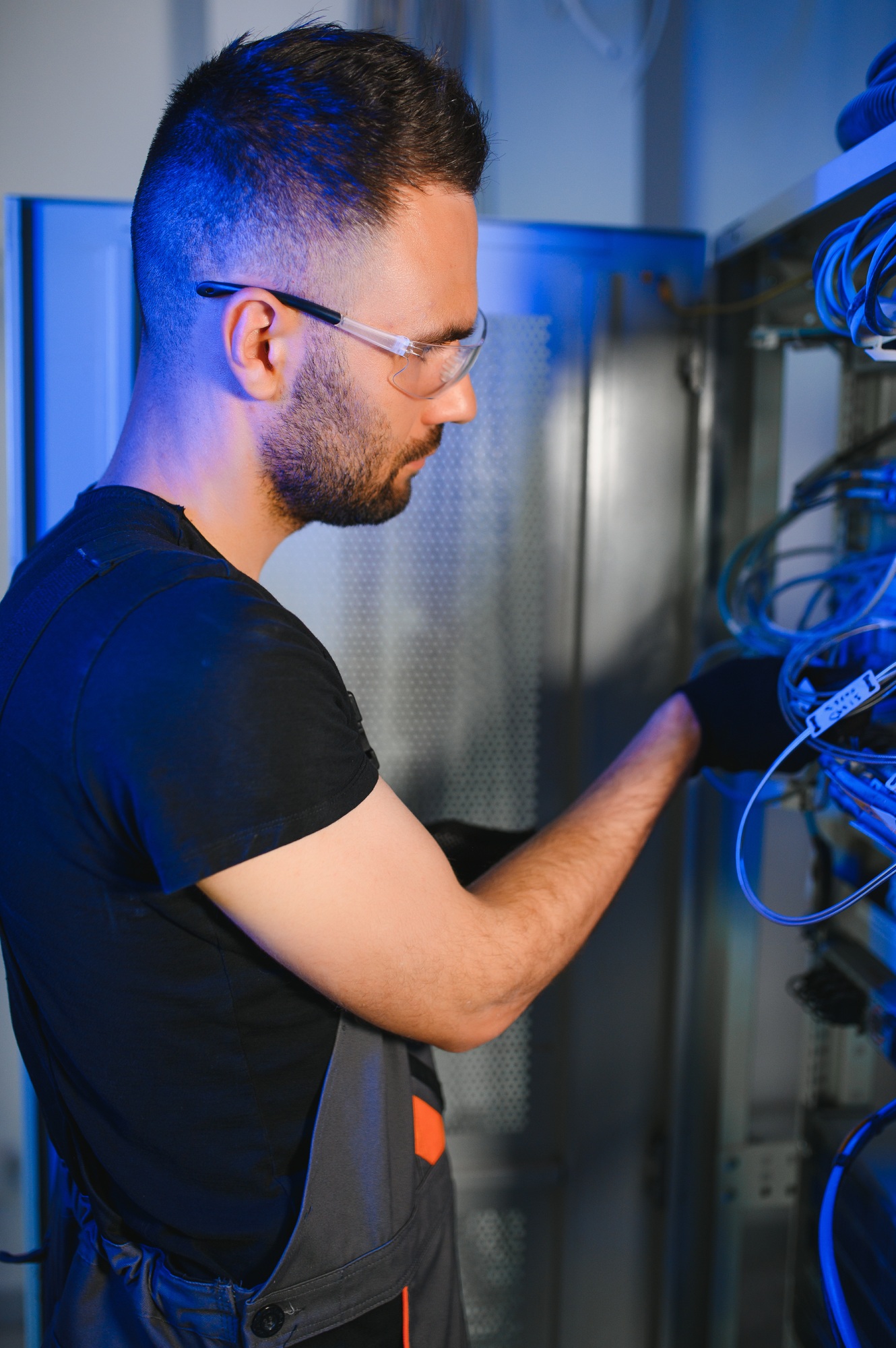 Young man is working with internet equipment and wires in server room